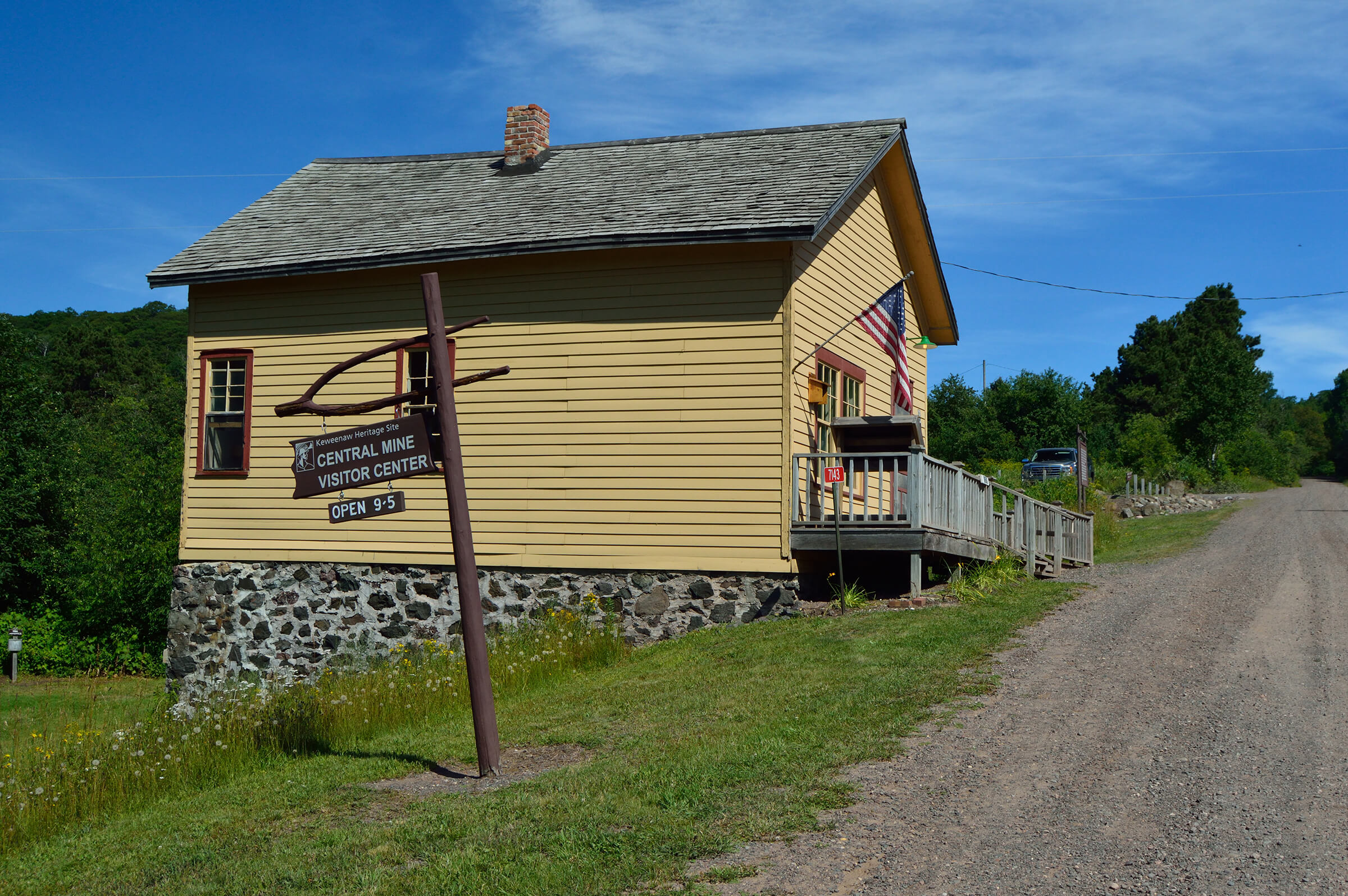 A yellow wooden building with a stone foundation, marked as the Central Mine Visitor Center.