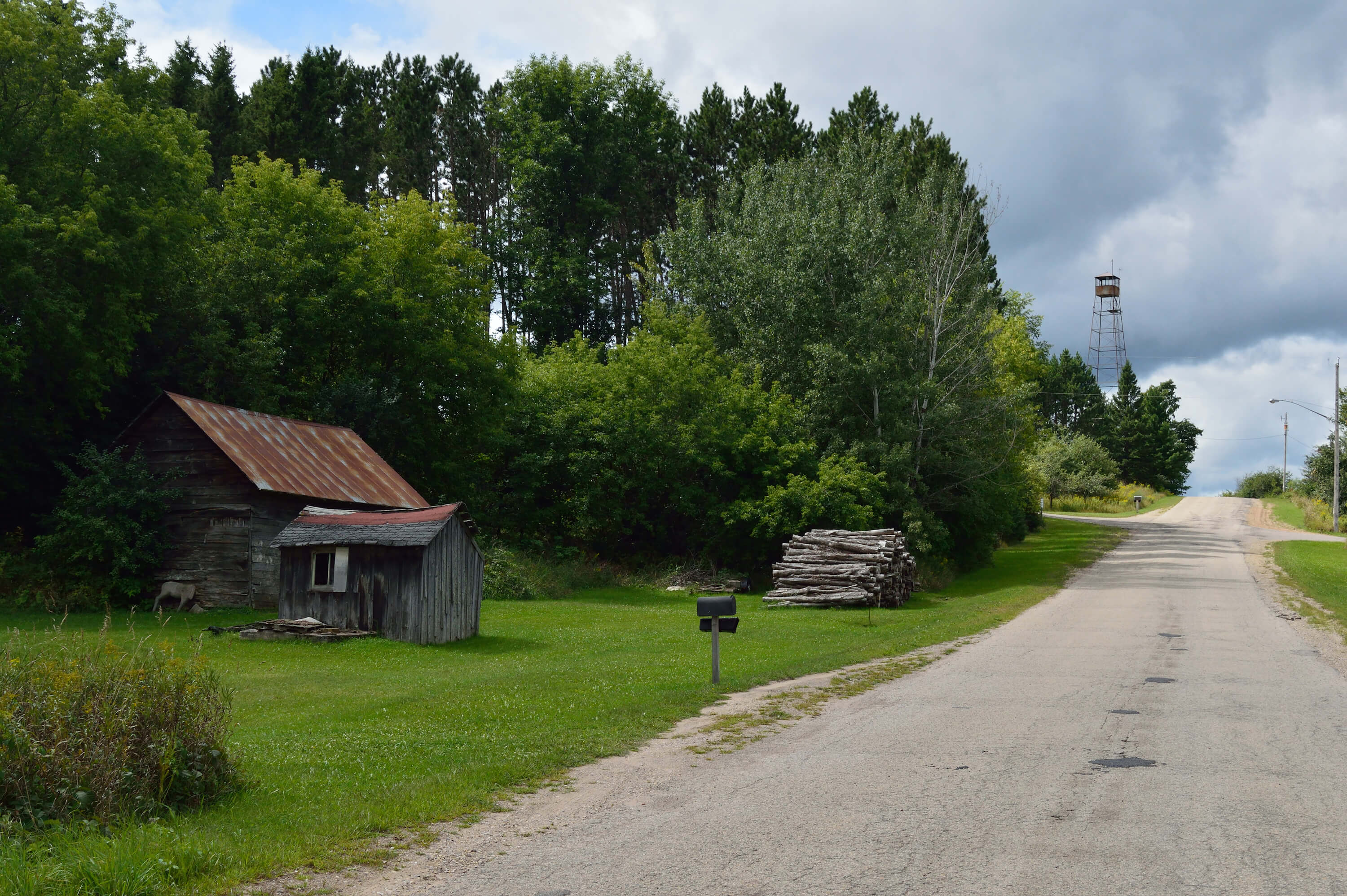 A rustic shed with a fire lookout tower in the distance.