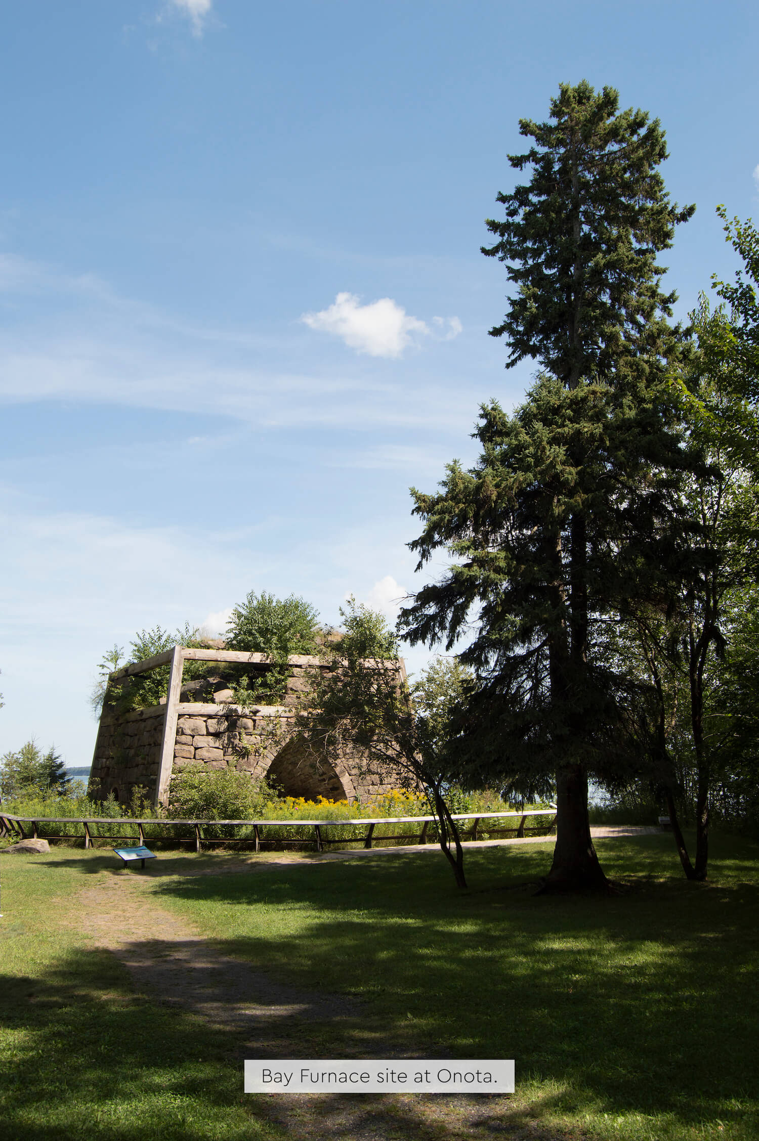 Historic Bay Furnace structure with trees and open sky.