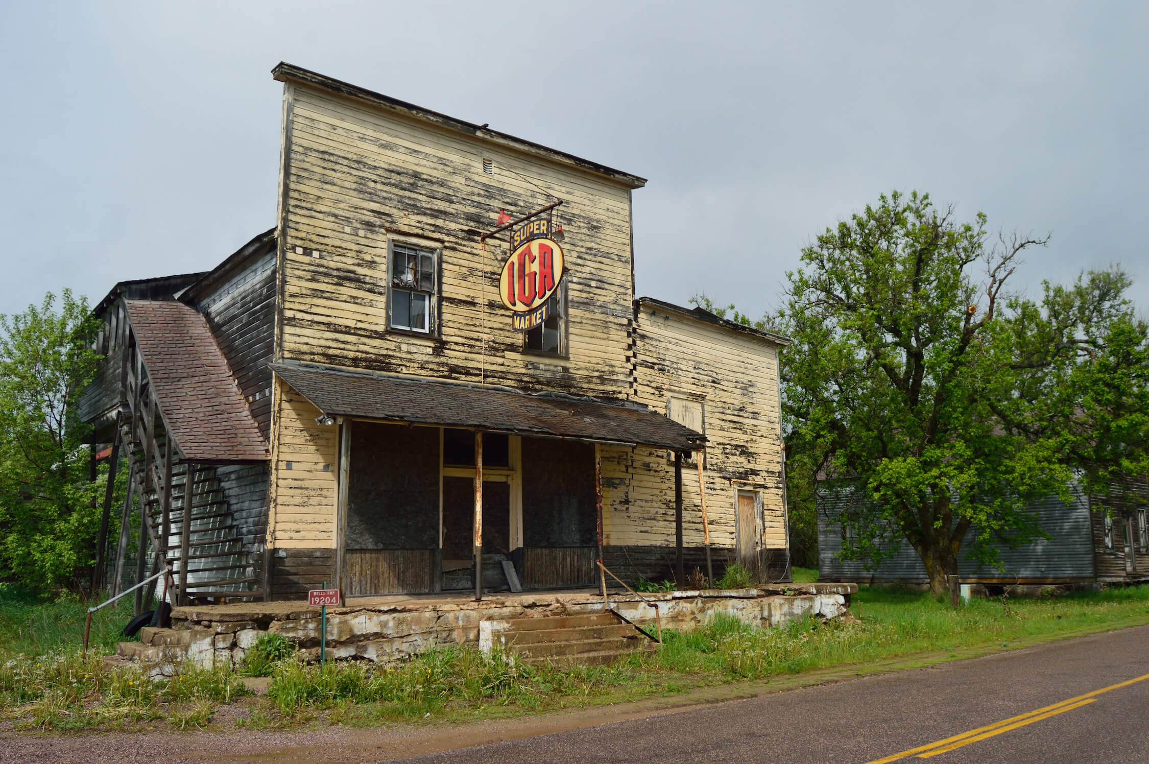 Abandoned wooden IGA store with faded paint and broken windows.