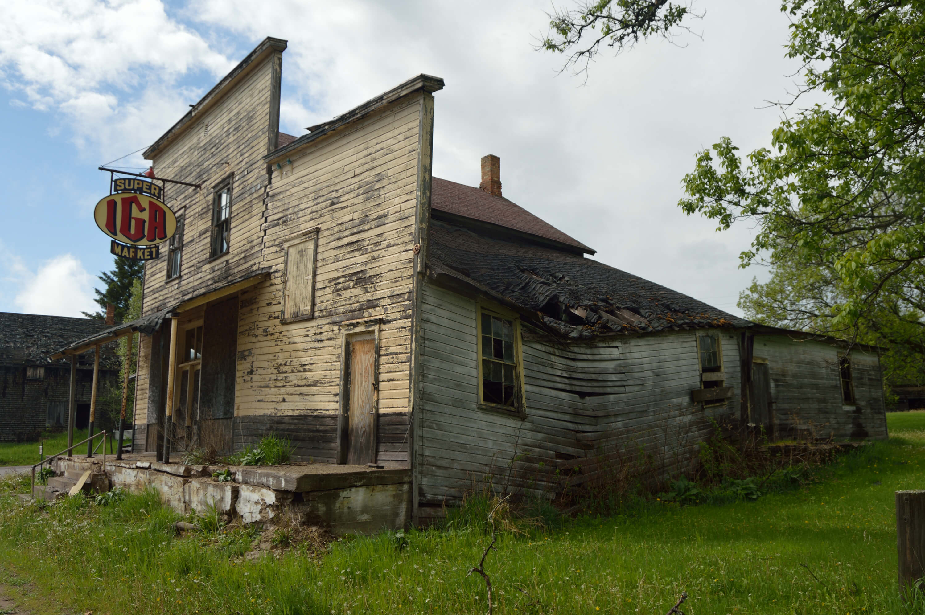 Dilapidated IGA store with a rusted sign and collapsed roof section.
