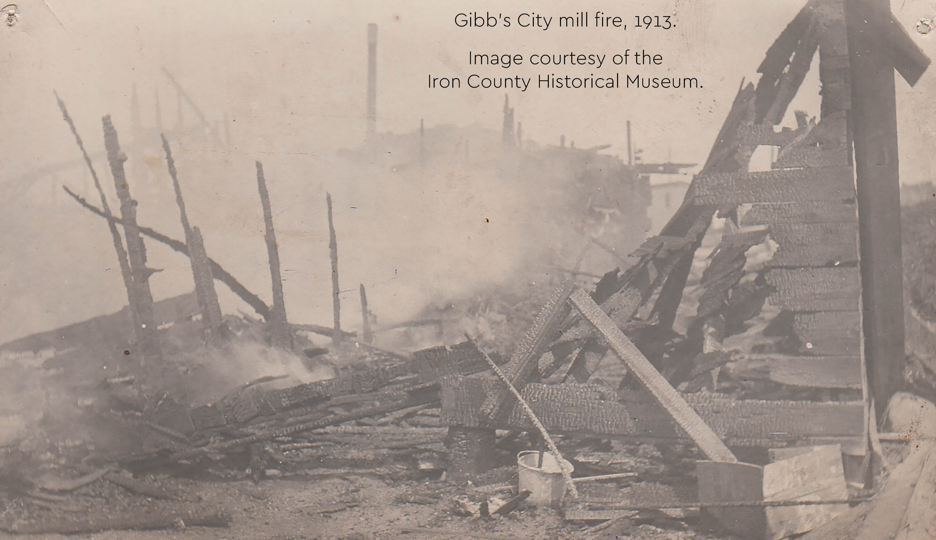 A historic photograph showing the charred remains of a mill after a fire.