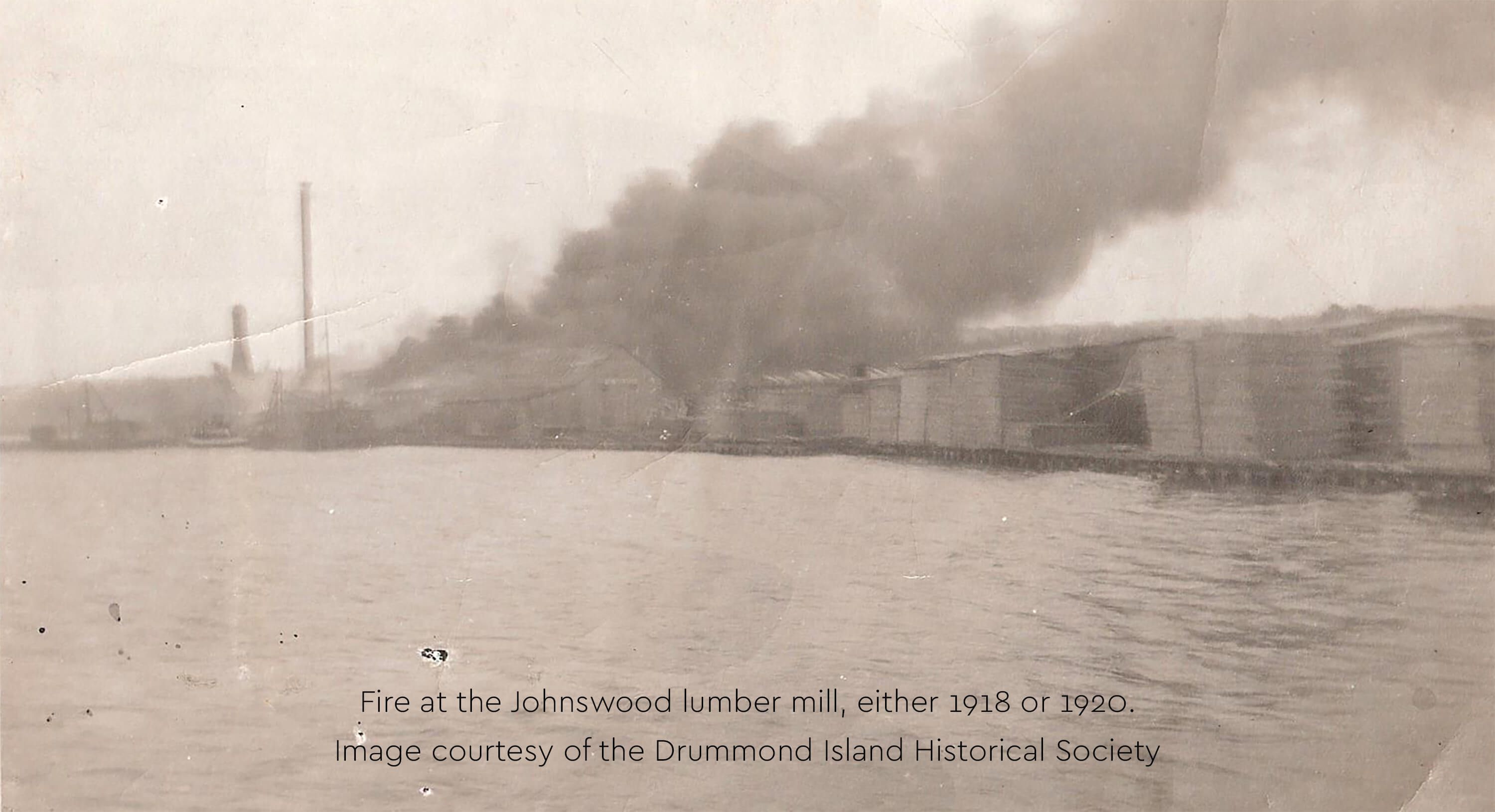 Historic image of fire at the Johnswood lumber mill with smoke billowing.