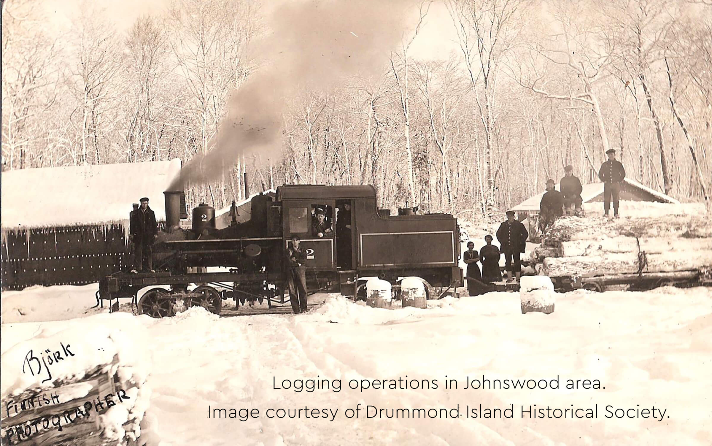 Historic image of a logging train and workers in Johnswood during winter.