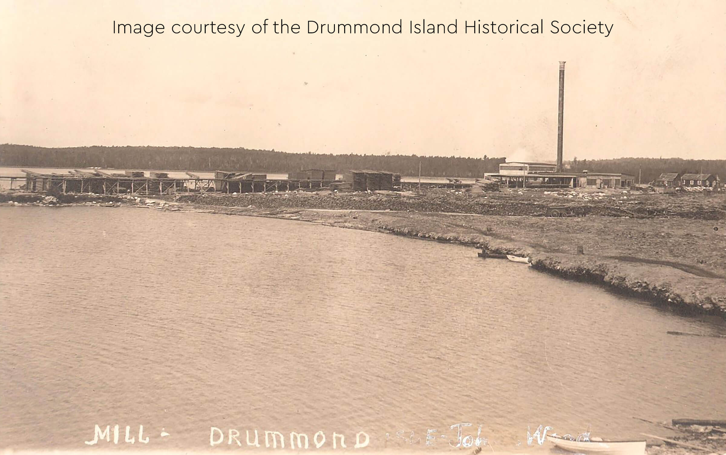 Historic image of the mill at Drummond Island with a smokestack by the water.