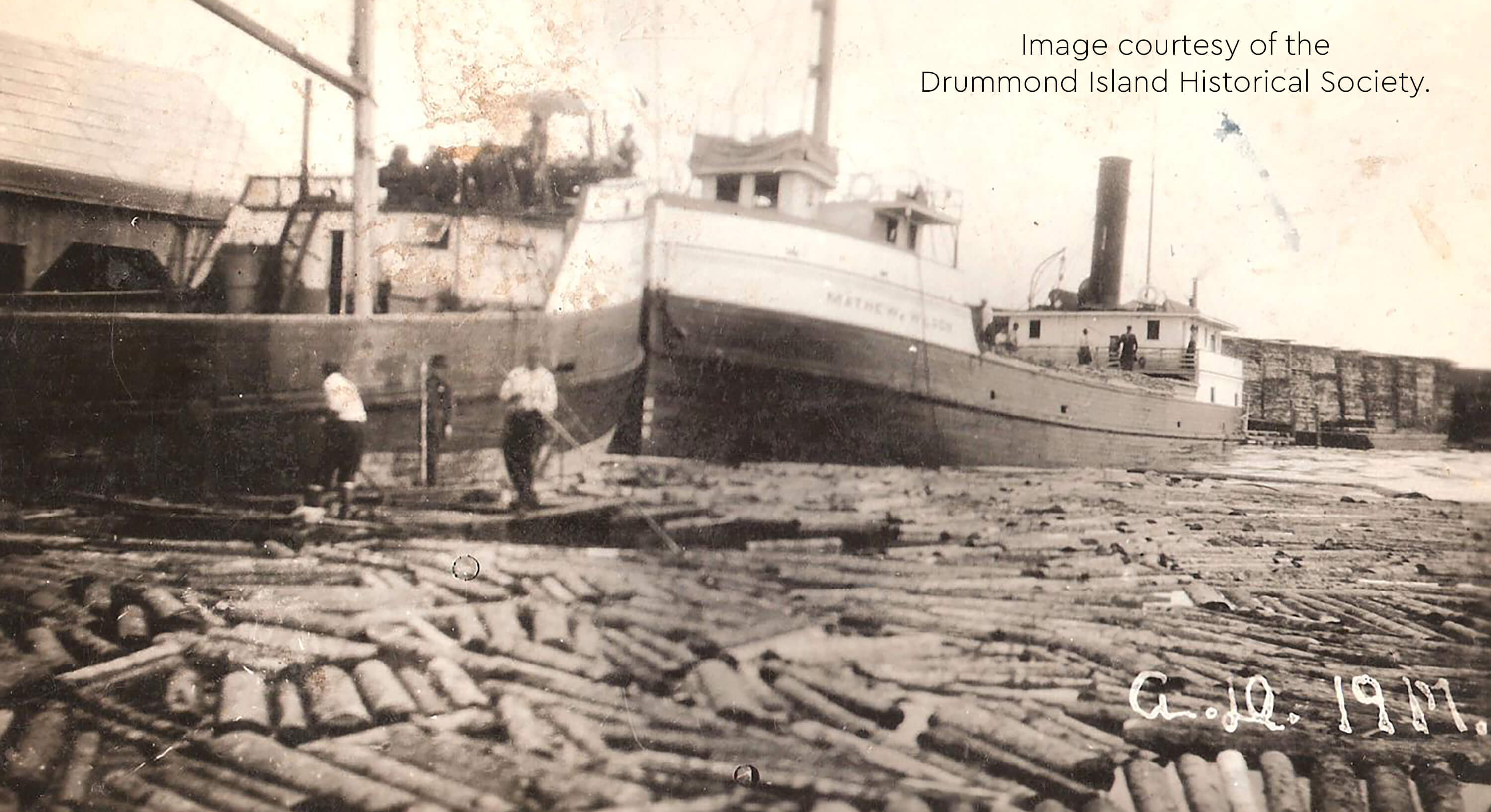 Historic image of logs being loaded onto the Matthew Wilson ship.