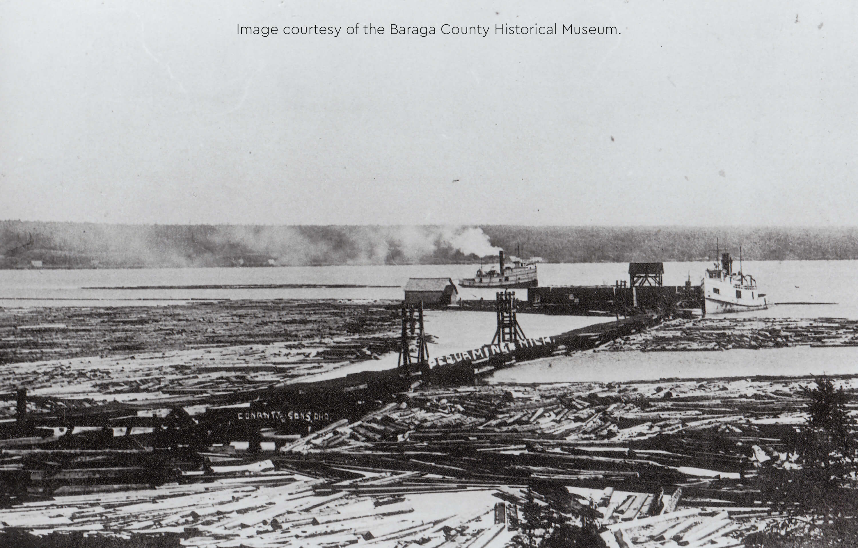 Historical image of Pequaming lumber operations with floating logs and a dock