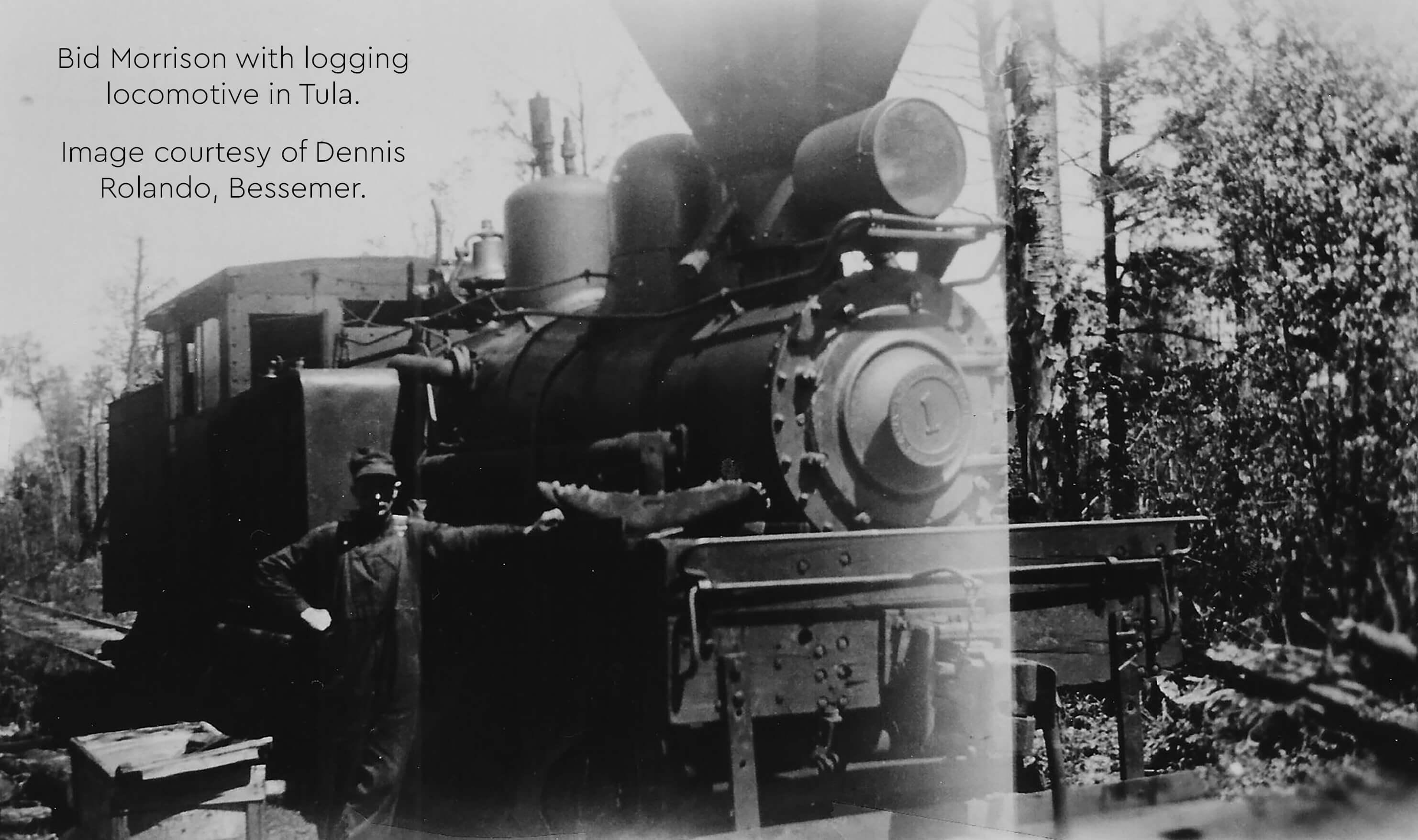 Historical photo of Bid Morrison standing beside a logging locomotive in Tula, Michigan.