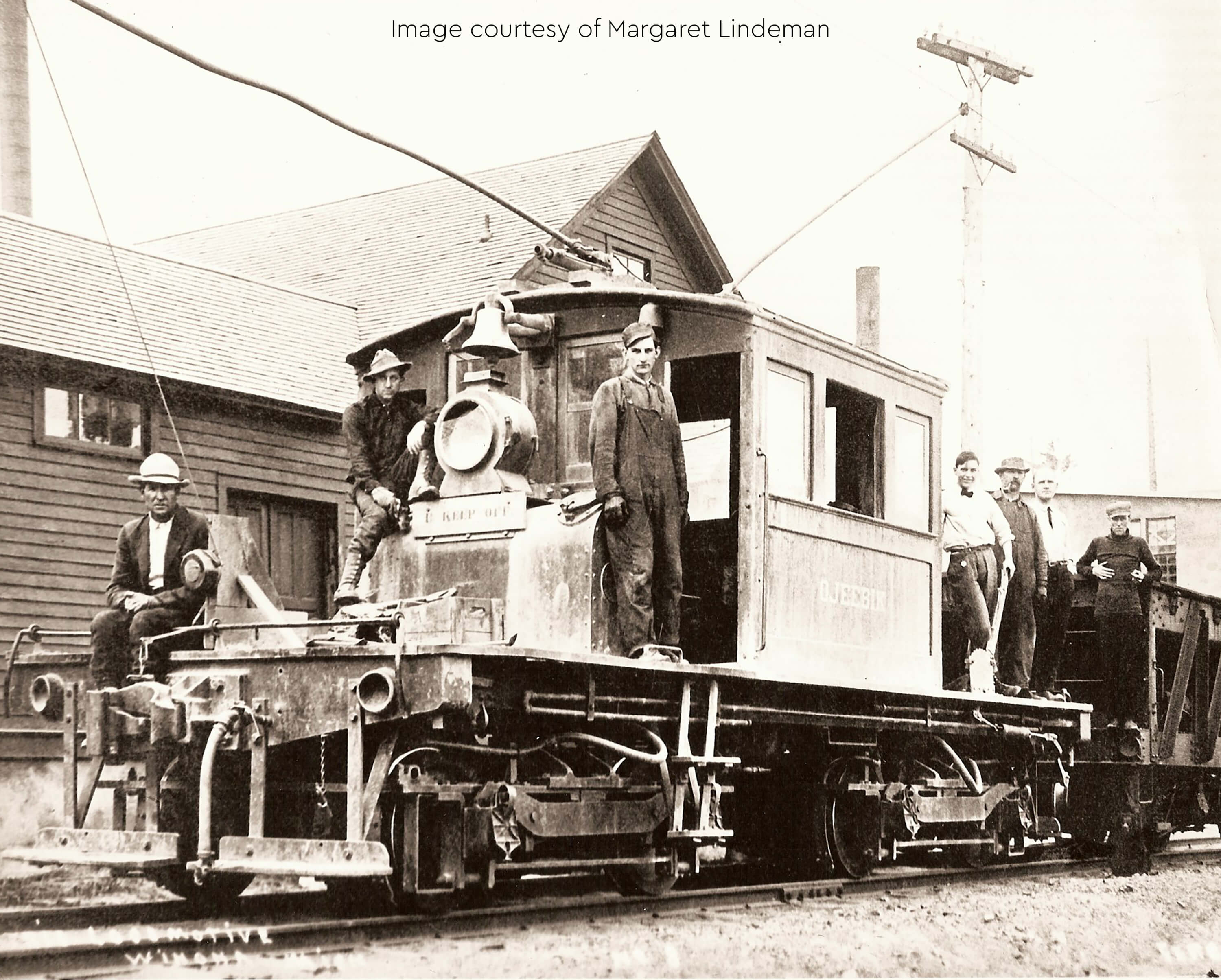 Historic photo of a mining locomotive with workers standing on and around it.