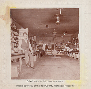A photograph of Ed Atkinson sitting on a bench inside a company store.