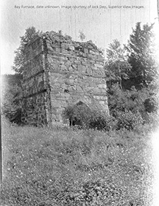 Historic Bay Furnace ruins surrounded by grass.