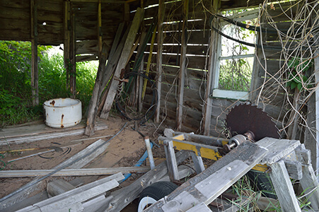 Inside an abandoned shed with tools and a rusty saw blade.