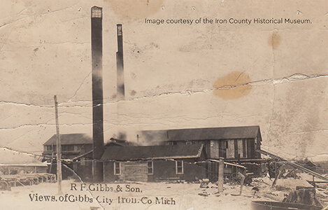 A historical photograph of the R.F. Gibbs & Son mill with two tall smokestacks.