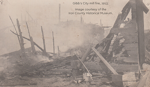 A historic photograph showing the charred remains of a mill after a fire.