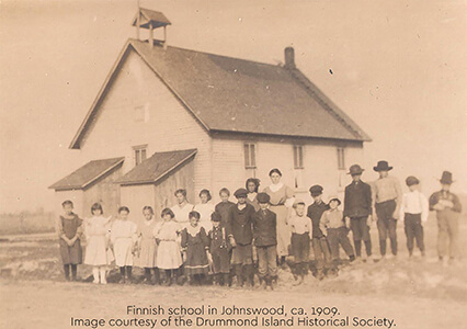 Historic photo of the Finnish school in Johnswood with children and adults in front.