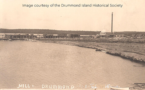 Historic image of the mill at Drummond Island with a smokestack by the water.