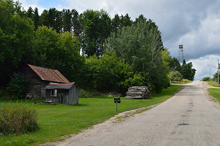 A rustic shed with a fire lookout tower in the distance.