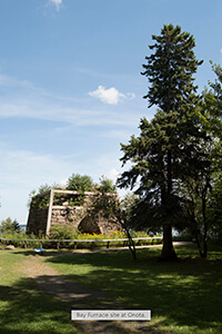 Historic Bay Furnace structure with trees and open sky.