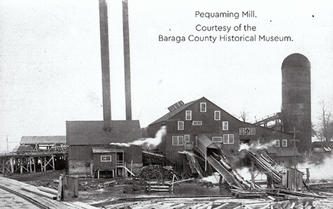 Historical image of Pequaming Mill with smokestacks and log conveyors
