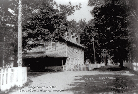 Historical image of the Pequaming Hotel with a tree-lined road