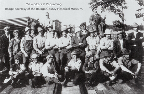 Historical image of mill workers in Pequaming posing on lumber stacks