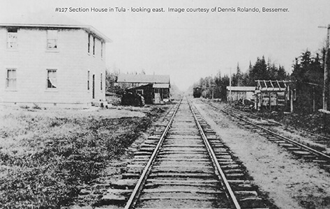 Historical photo of the Tula Section House beside railroad tracks, looking east.