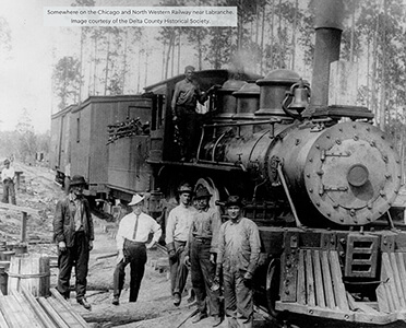 Historic steam locomotive with crew members posing on and around it.