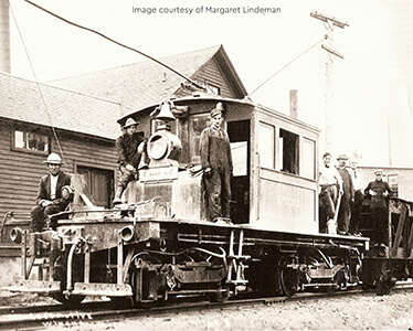 Historic photo of a mining locomotive with workers standing on and around it.