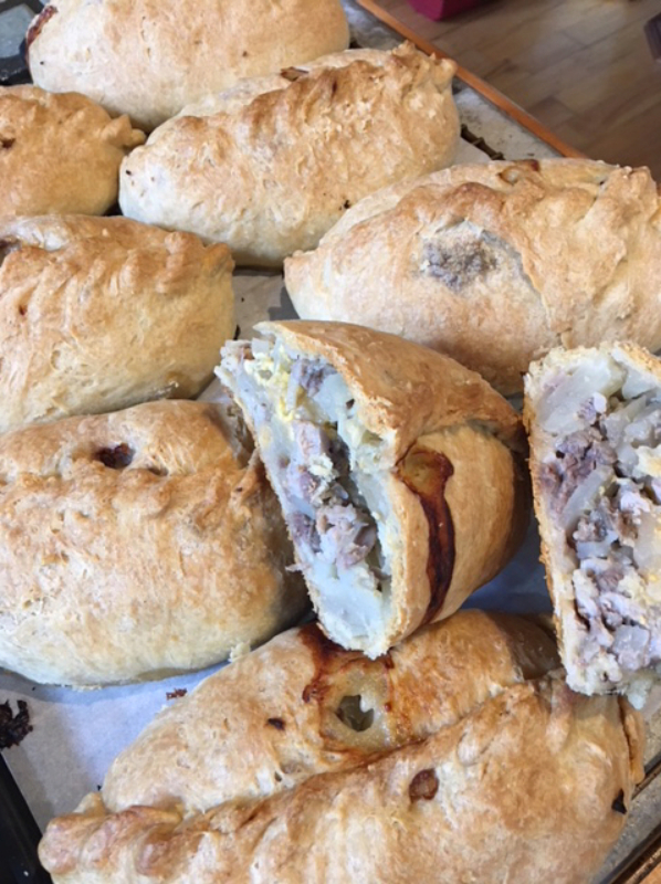 Stacked pasties with one sliced open showing the filling.