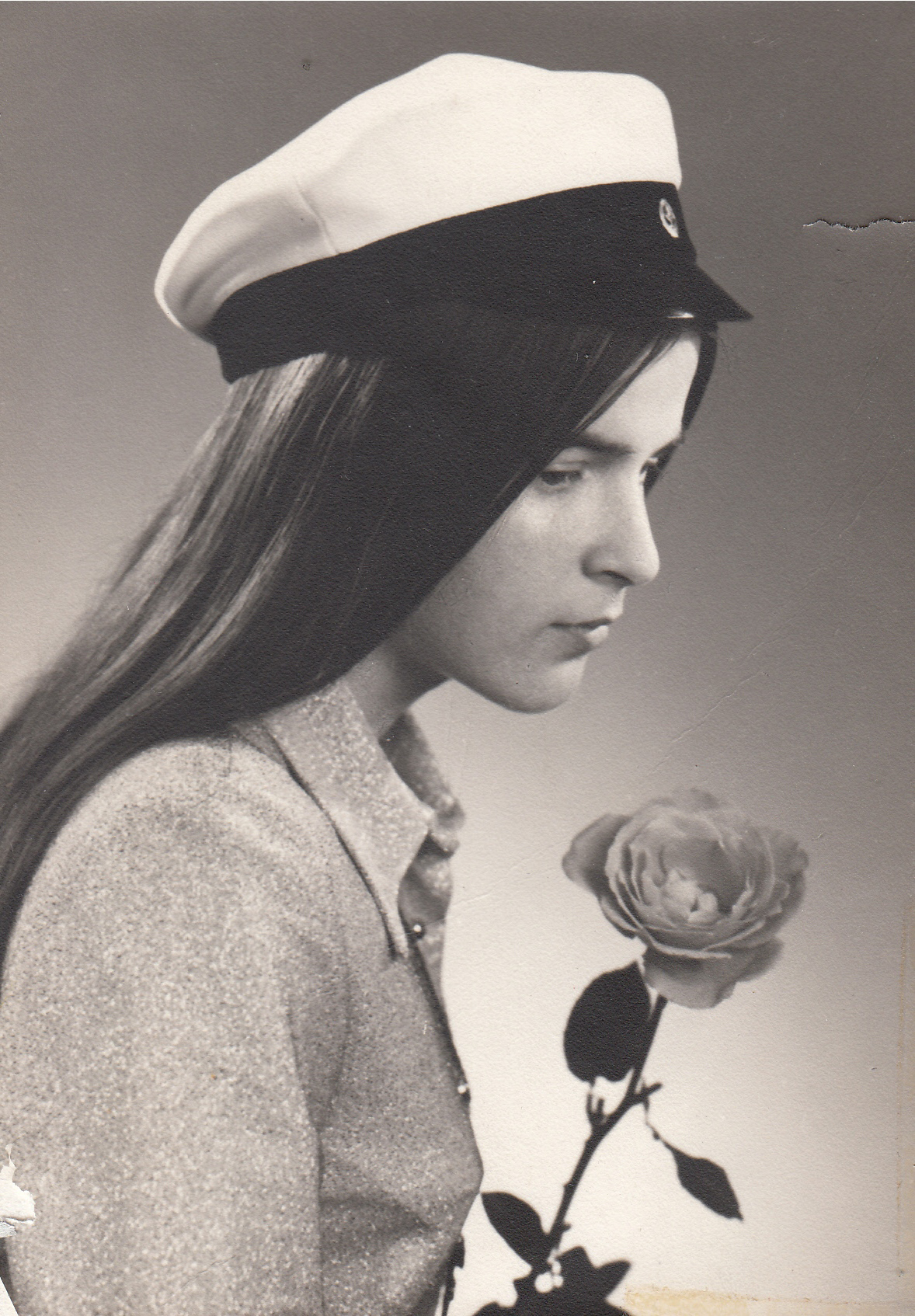 Tanja in a graduation cap gazes at a rose in profile.